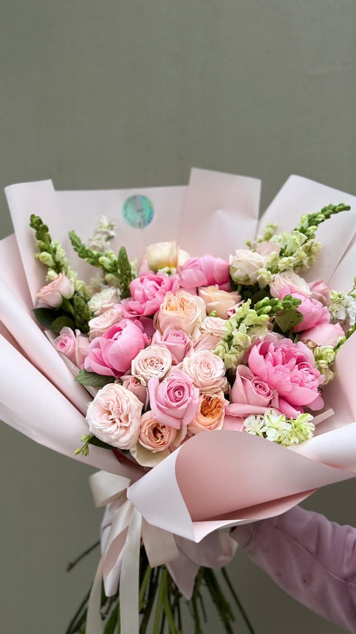 Ramo fresco de peonías y rosas en papel rosa