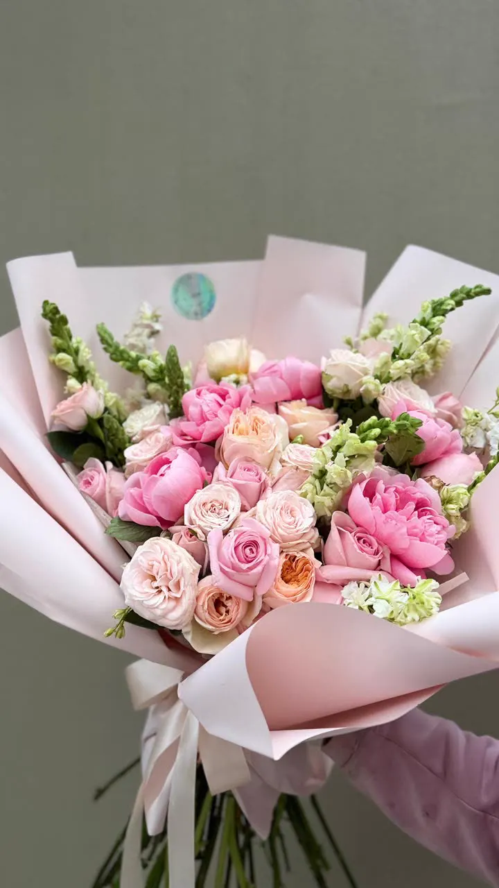 Ramo fresco de peonías y rosas en papel rosa